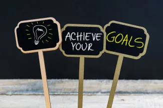Concept message ACHIEVE YOUR GOALS and light bulb as symbol for idea