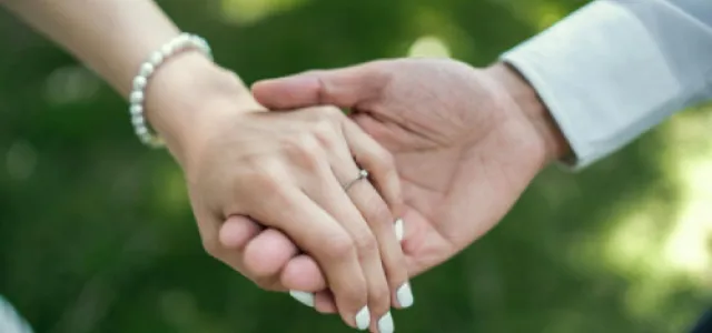 a man and woman holding hands in the grass